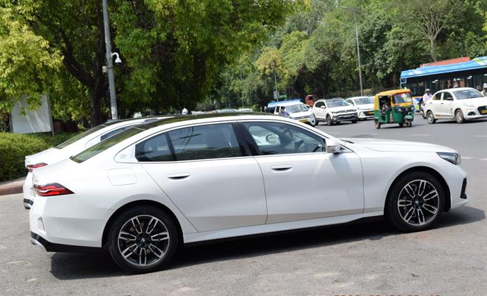 BMW 530Li in profile on a Delhi arterial road during a chauffeured transfer
